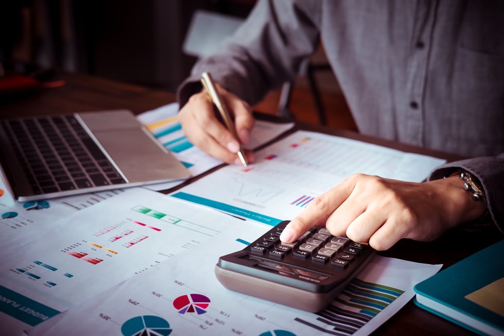 Person Working with Calculator and Notebook on Table